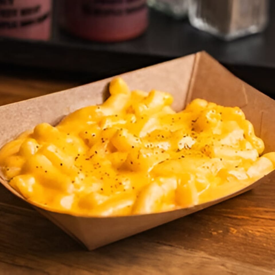 Creamy mac and cheese with black pepper in a brown paper tray from Double D's Southern BBQ.