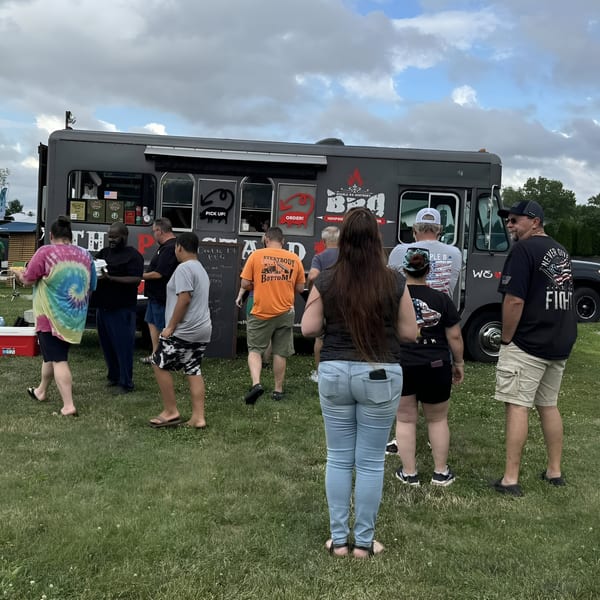Customers line up at the Double D's Southern BBQ food truck on a grassy field.